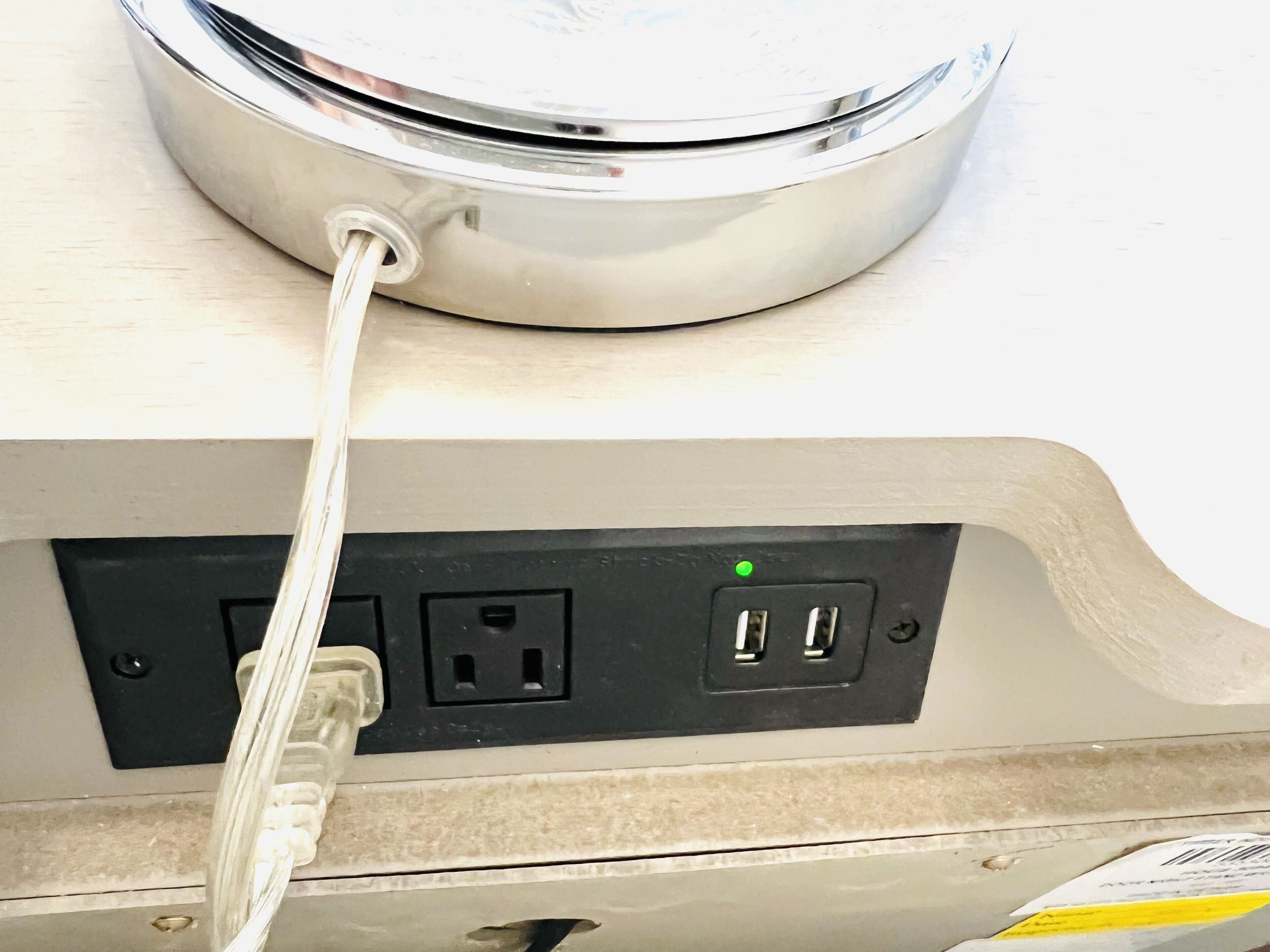 Een metalen apparaat met een kabel aangesloten op een stopcontact.