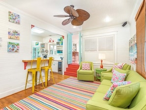 Relax in this inviting living room with a green sofa, colorful artwork, and a large window.
