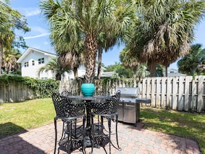 Enjoy al fresco dining on the patio, surrounded by lush greenery and a grill for outdoor cooking.