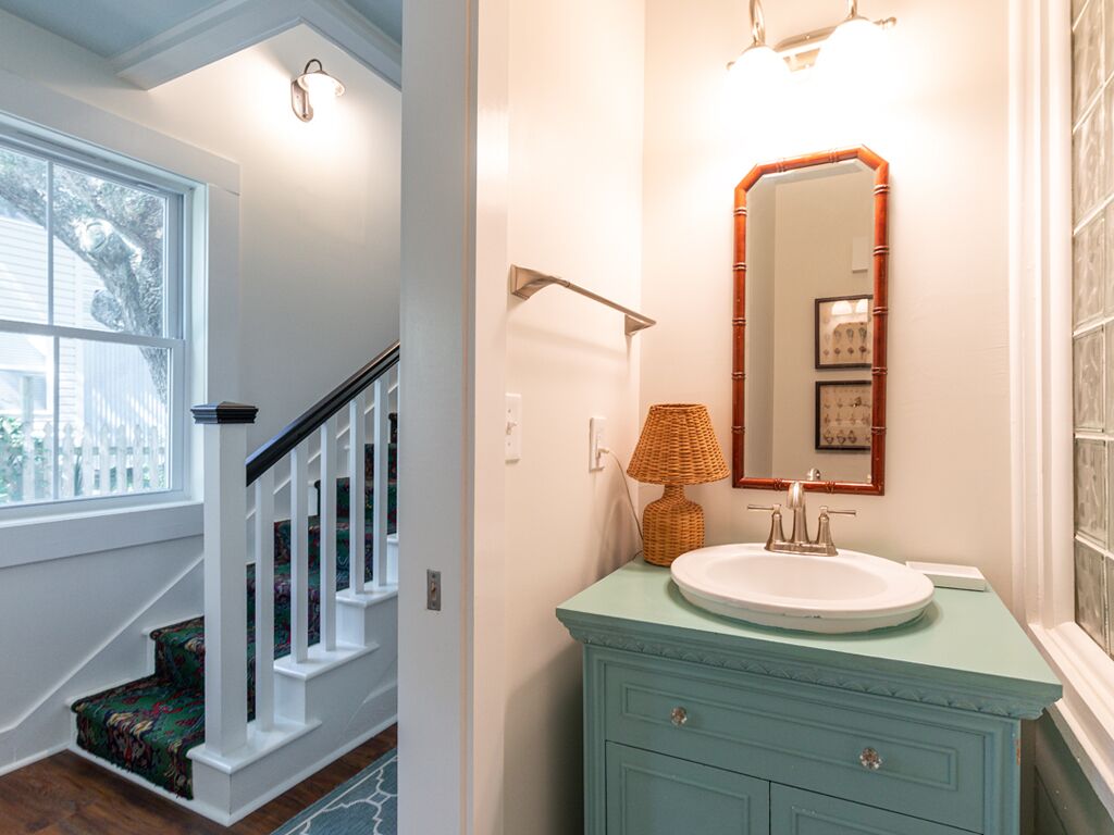 A bathroom with a white sink, a mirror with a bamboo frame, and a wicker lamp.