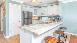Una cocina moderna con armarios blancos, un refrigerador de acero inoxidable, un microondas y una isla grande con taburetes.