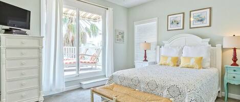 A bedroom with a bed, a bench, a dresser, a television, and a ceiling fan.