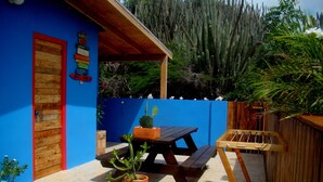 A patio area with wooden benches, a table, and a potted cactus. - Hopi Cadushi Apartment (Cashero)