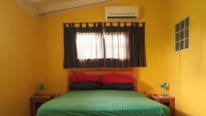 A single-bed room with a wooden headboard, a green bedspread, and two bedside tables with lamps. - Hopi Cadushi Apartment (Cashero)