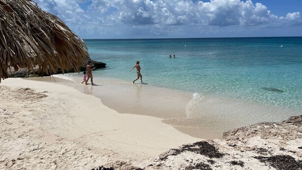 A beach with clear turquoise water, a thatched structure, and a sandy shore. - Hopi Cadushi Apartment (Cashero)