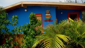A building with a blue exterior and red-framed windows. There are multiple signs on the wall, including one that says "New York." - Hopi Cadushi Apartment (Cashero)
