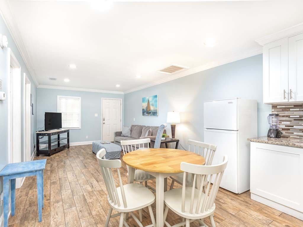 A compact living space with a dining area, kitchenette, and a television in the corner.