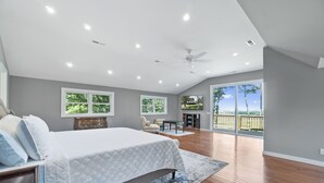 A spacious bedroom with a large bed, a ceiling fan, and a balcony with a view of the outdoors. - Mountain View Cabin in VA Wine Country (Scottsville)