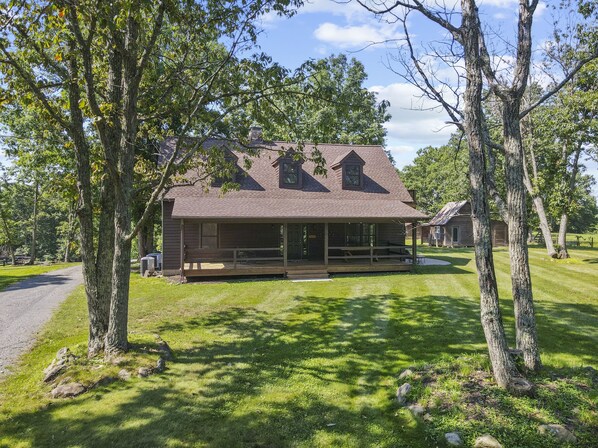 A rustic cabin with a porch, surrounded by trees and a well-maintained lawn. - Mountain View Cabin in VA Wine Country (Scottsville)