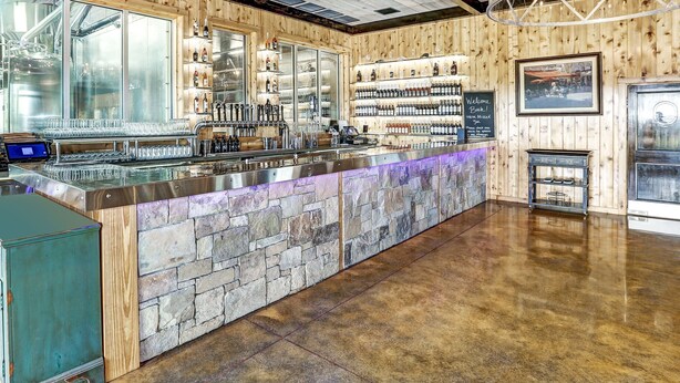 A bar area with a stone counter, wooden walls, and a modern chandelier. - Mountain View Cabin in VA Wine Country (Scottsville)