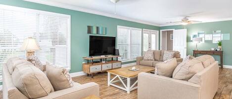 A living room with two sofas, a coffee table, a TV, and a ceiling fan.