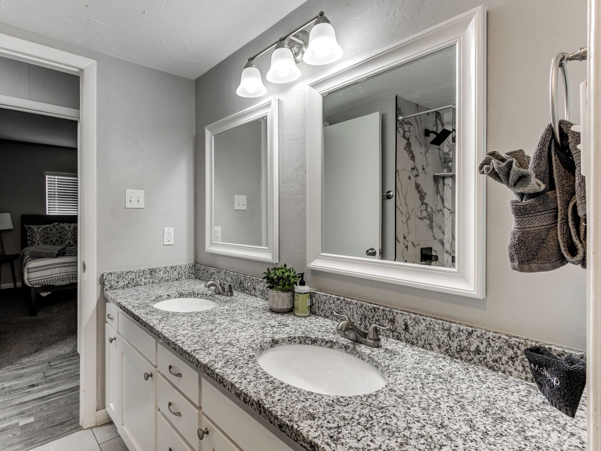 A bathroom with two sinks, a large mirror, and a towel rack.