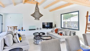A modern living room with a sofa, two round coffee tables, a TV, and a large window.
