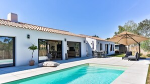 A modern house with a swimming pool, outdoor seating, and a patio area.