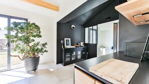 A modern kitchen with a large island, black cabinetry, and a potted tree.
