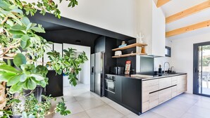 A modern kitchen with black cabinetry, a central island, and wooden beams on the ceiling.