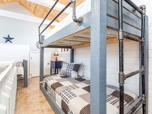 A bunk bed room with a star decoration, a lamp, and a door. - Free Bird by Tybee Vacation Rentals (Tybee Island)