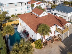 A residential building with a swimming pool, a red-tiled roof, and a balcony. - Free Bird by Tybee Vacation Rentals (Tybee Island)