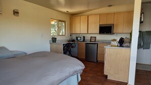 Une chambre compacte dotée d’un grand lit et d’un coin cuisine comprenant un four à micro-ondes, un réfrigérateur et des placards en bois.