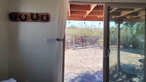 Une pièce dotée d’une porte-fenêtre coulissante donnant sur un patio extérieur, agrémenté d’une clôture en métal et d’une pergola en bois.
