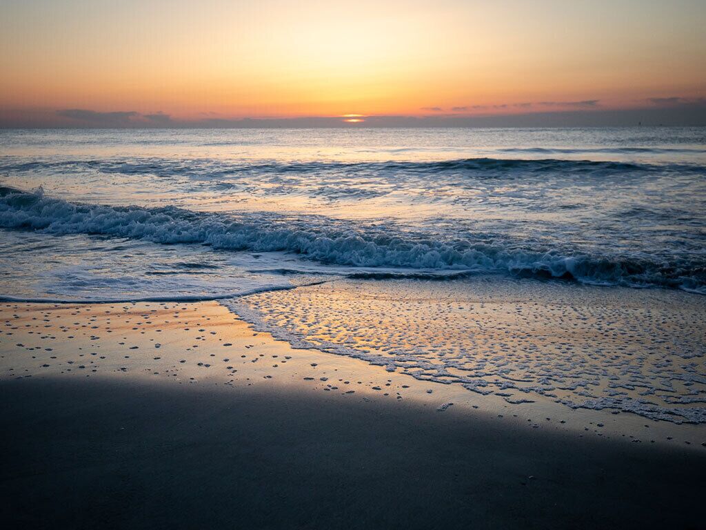 A beach with waves at sunset.