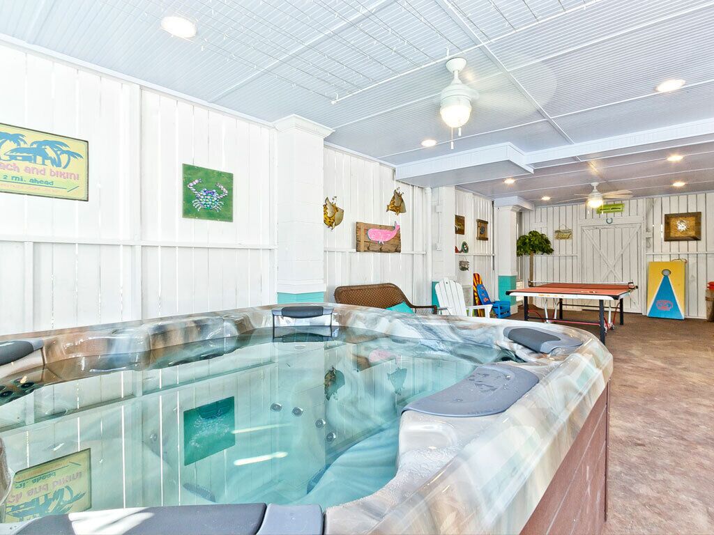 A spa area with a hot tub, white walls, and various artwork.