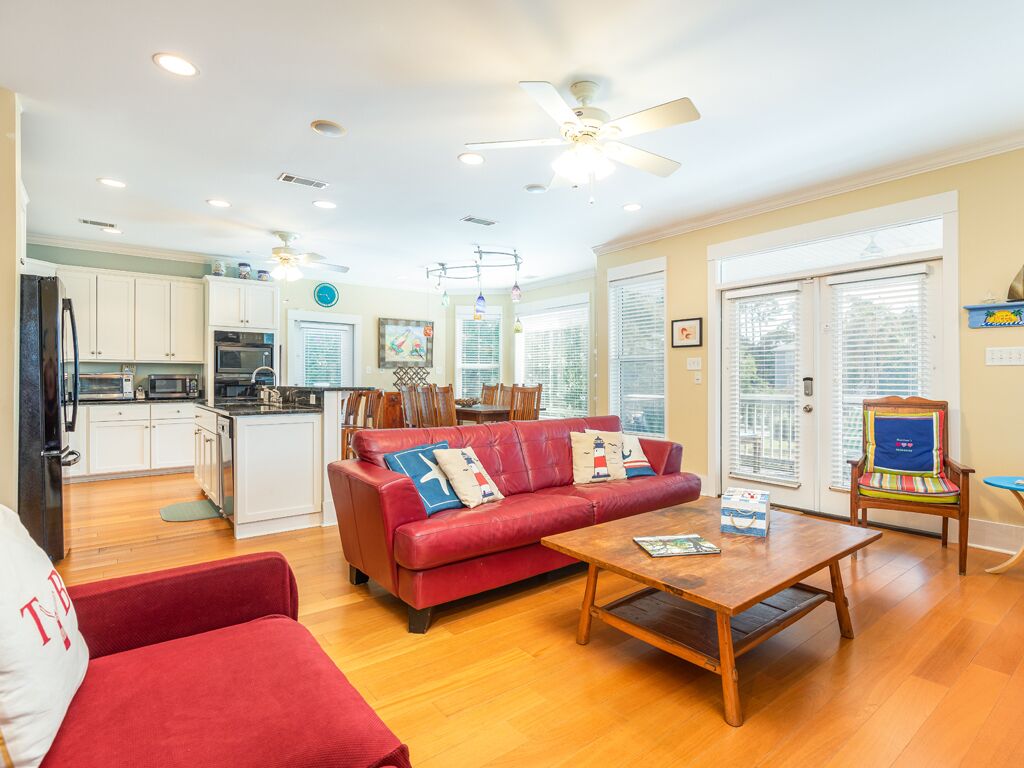A spacious living area with a red sofa, wooden coffee table, and a ceiling fan.