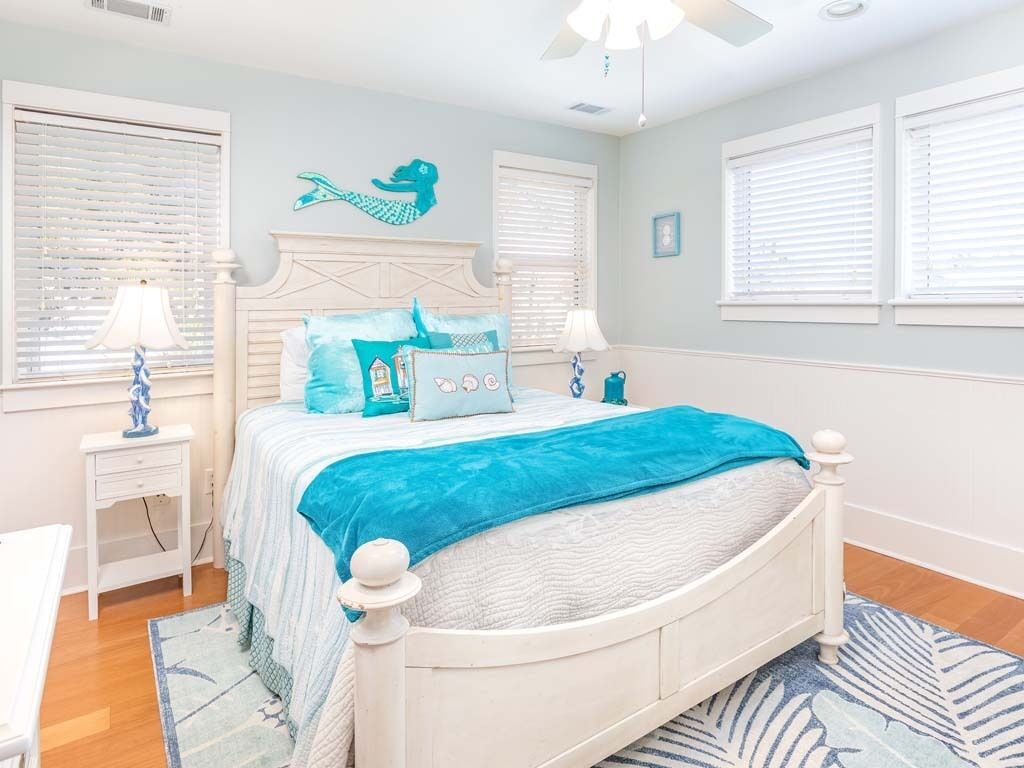 A bedroom with a bed, two bedside tables, a ceiling fan, and a window with blinds.