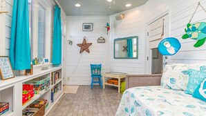 Una habitación acogedora con una cama, un escritorio y estantes llenos de libros y juguetes.