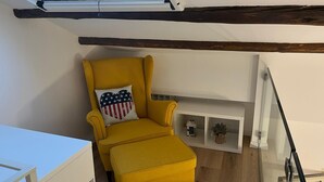 A yellow armchair with a heart-shaped pillow, a small shelf with decorative items, and a skylight above. - Finely renovated house, a few steps from the sea (Isola delle Femmine)