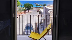 A balcony with a yellow chair, a view of the sea, and a street with parked cars and a no parking sign. - Finely renovated house, a few steps from the sea (Isola delle Femmine)
