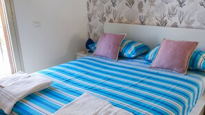 A bed with a striped blue and white bedspread, two pillows, and two folded towels. - Finely renovated house, a few steps from the sea (Isola delle Femmine)