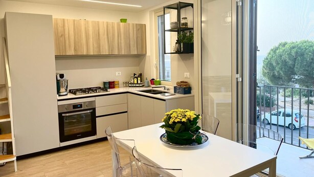 A modern kitchen with a dining area, featuring a large window with a view of the outside. - Finely renovated house, a few steps from the sea (Isola delle Femmine)