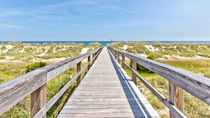 A wooden boardwalk leading to the beach with dunes in the background. - High Tide by Tybee Vacation Rentals (Tybee Island)