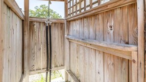 Un área de estar exterior de madera con una pérgola, un poste de metal y un banco de madera.