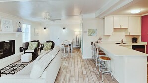 Una sala de estar moderna con chimenea, un comedor y una cocina con barra.