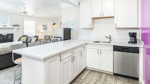 Una cocina moderna con armarios blancos, lavavajillas integrado y cafetera.