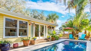 A poolside area with a house, potted plants, and outdoor furniture. - Island Bliss Tybee Vacation Rentals (Tybee Island)