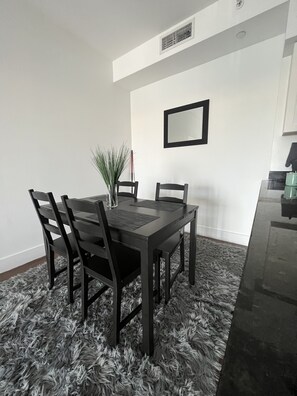 Enjoy meals in this cozy dining area with a table for four, a potted plant, and a view of the adjacent kitchen.