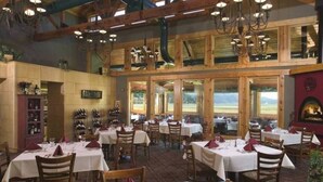 Un restaurant doté de nombreuses tables et chaises, de grandes fenêtres et d’une cheminée.