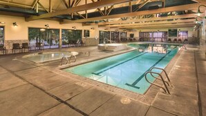 Une piscine intérieure avec des couloirs clairement délimités, un jacuzzi et des chaises longues.