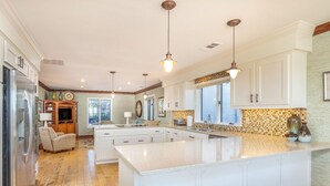 A spacious kitchen with white cabinetry, a large island, and a wooden floor.