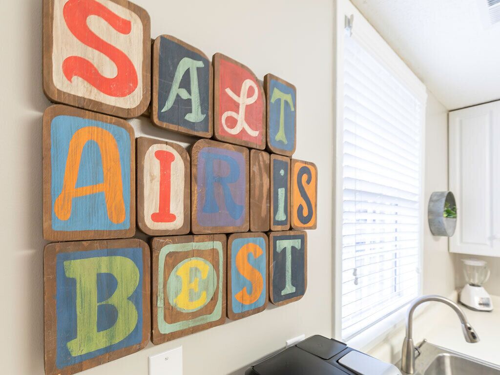 A kitchen with wooden blocks spelling "SALT AIR IS BEST" on the wall.