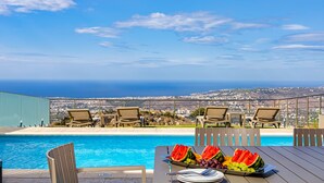 A poolside area with a table set for a meal, overlooking a cityscape and the sea. - Villa Mari Chania with ecologic private pool and amazing view. (Chania)