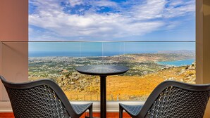 A balcony with a round table and two chairs, overlooking a coastal landscape with buildings and a body of water. - Villa Mari Chania with ecologic private pool and amazing view. (Chania)