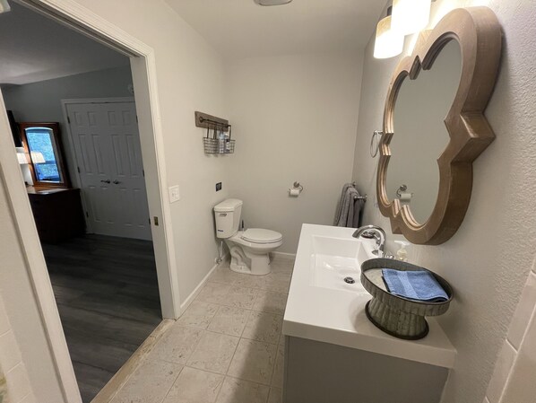 A bathroom with a toilet, sink, and mirror. - The Inn at Dirickson Creek - Room Three (Frankford)
