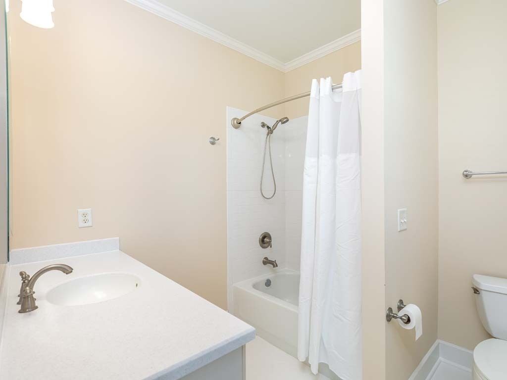 Un baño con lavamanos, bañera, cortina de ducha, inodoro y un perchero para toallas.