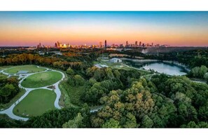 An aerial view of a cityscape with a river, parks, and a skyline at sunset.
