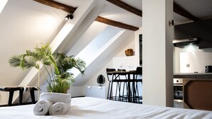 Quarto de hotel com cama, planta em vaso e área de refeições com mesa e cadeiras.