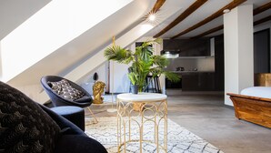 Um loft moderno com pé-alto, vigas de madeira aparentes, área de jantar com mesa redonda e cozinha ao fundo.